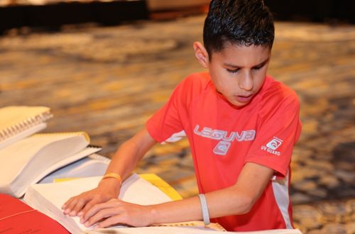 Young boy reads a Braille book